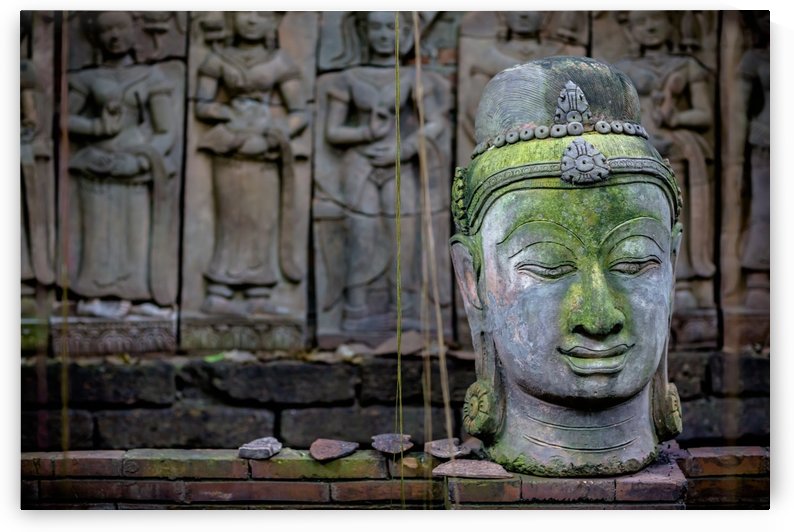 A terra cotta head of buddha sits in front of bas-relief in a terra cotta garden; Chiang Mai, Thailand by PacificStock
