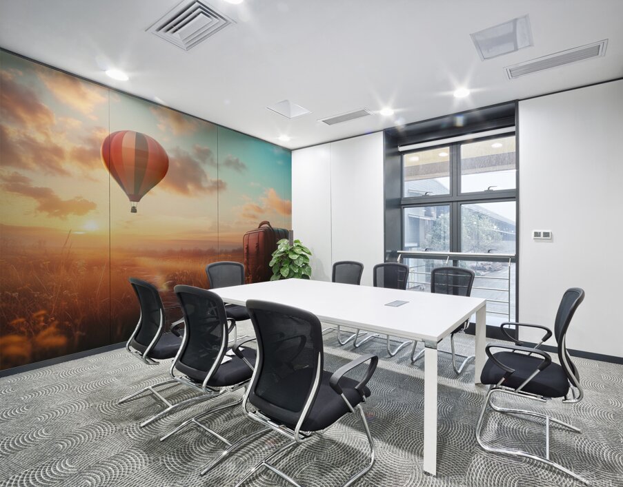 Colorful hot air balloon rises above grassy field with suitcase at sunset Wall Printing