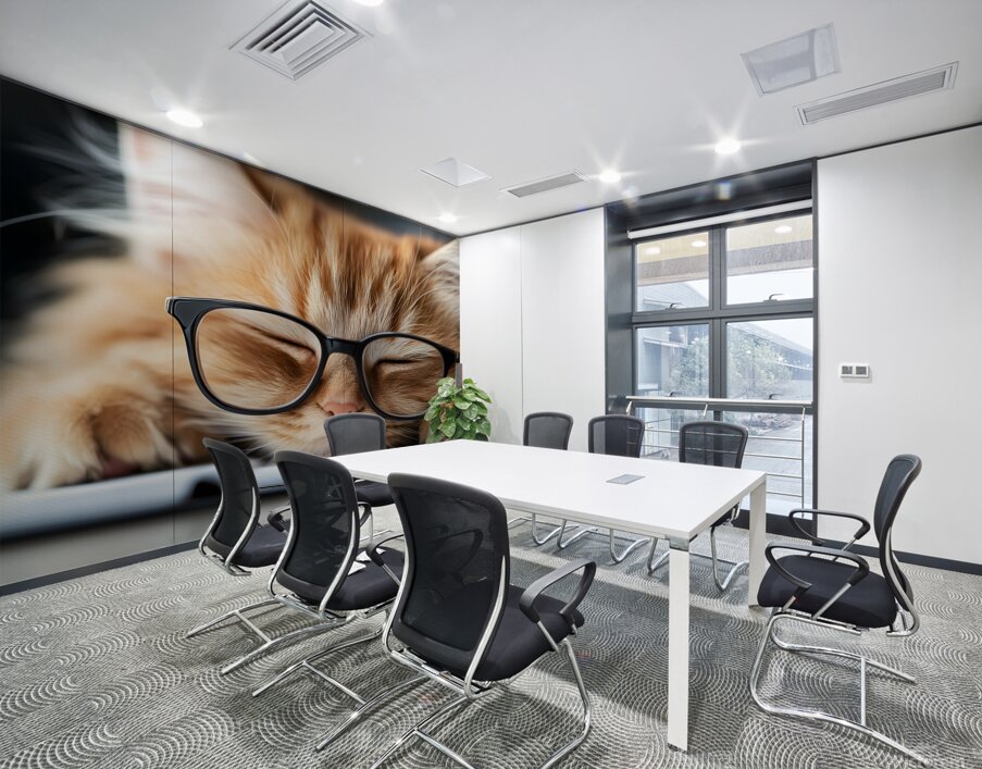 A fluffy orange cat with metal glasses frame is peacefully napping on a notebook. Its eyes are closed creating a serene atmosphere in a warm and inviting indoor space. Wall Printing