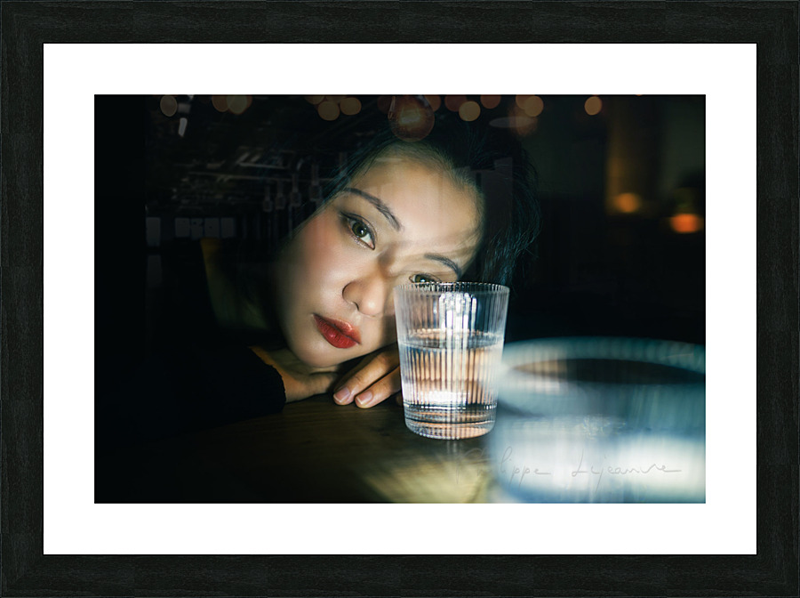 Young woman looking through a glass of water Picture Frame print
