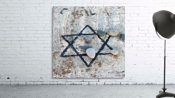 A star of david etched and painted on a rock with stones laying on it Wall Preview