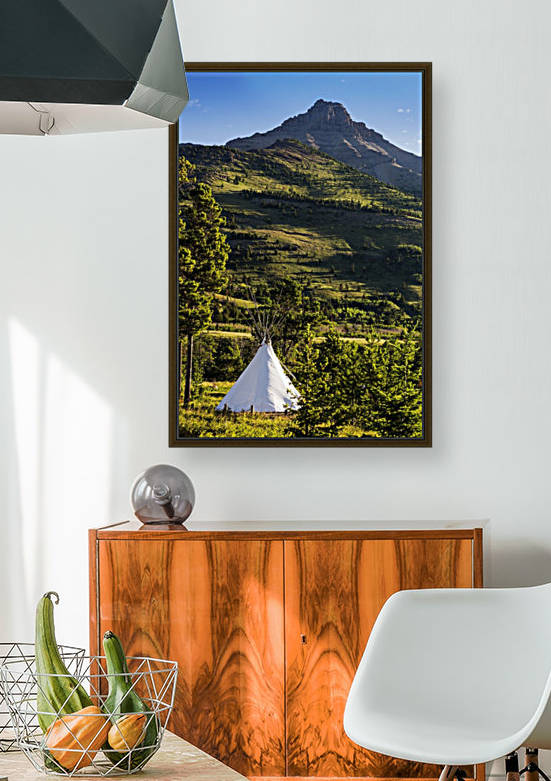 Large white canvas teepee in a treed field with green hillside and mountain peak in the background; Waterton, Alberta, Canada by PacificStock