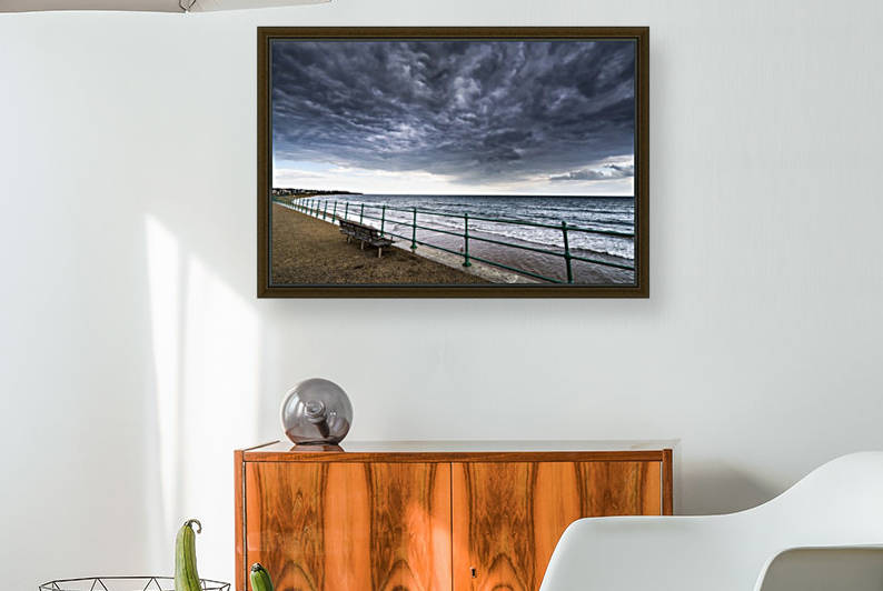 Green metal railing and bench along the water under dark storm clouds; Sunderland, Tyne and Wear, England by PacificStock