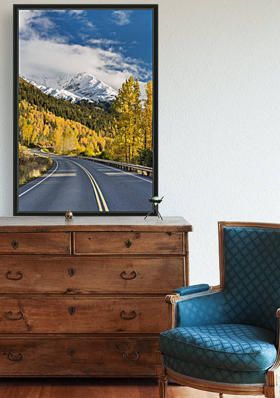 Snow-capped Kenai Mountains dwarf the Seward highway, trees covered in yellow leaves in autumn line the road, South-central Alaska; Seward, Alaska, United States of America by PacificStock