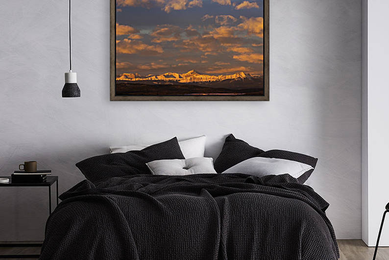 Glowing warmly lit snow covered mountain range and foothills with glowing clouds and blue sky at sunrise; Calgary, Alberta, Canada by PacificStock