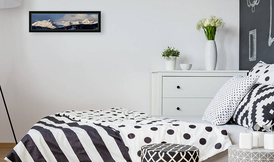 Panorama of snow covered mountains with early morning light, silhouetted forest in the foreground, blue sky and clouds; Kananaskis Country, Alberta, Canada by PacificStock