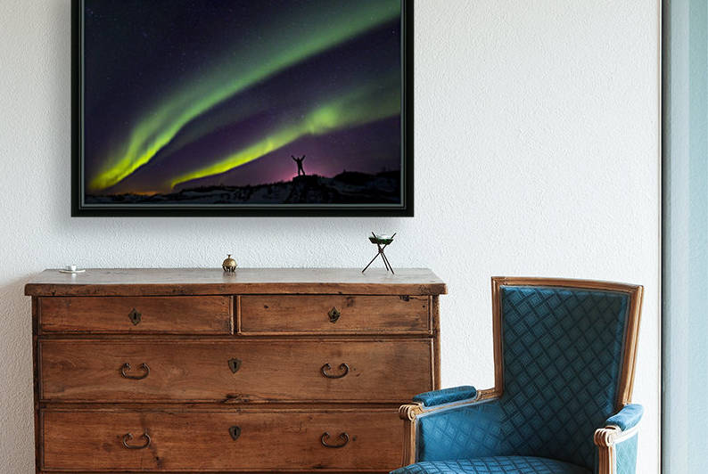 Colourful Aurora borealis over a man with arms outstretched silhouetted against light pollution from nearby Fort Greely; Alaska, United States of America by PacificStock