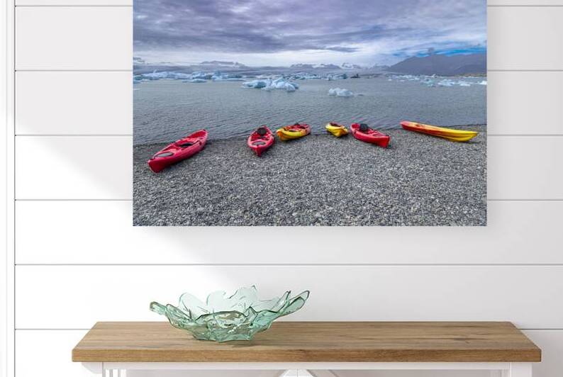 Colorful kayaks resting on a rocky beach awaiting kayakers in ic by Gualtiero Boffi