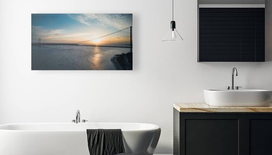 Sunset over a calm river with a silhouette of a suspension bridge against a colorful sky in Hull England. by Vasile Jechiu