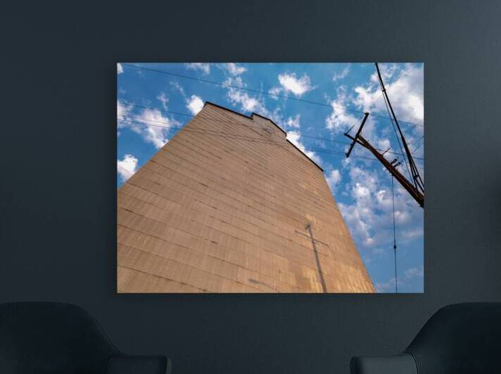 Power poles cast shadows on the corrugated metal wall of an old grain elevator in the early morning by David Reinhold