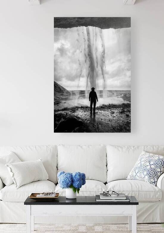 Man wearing hat standing behind waterfall in iceland by Gualtiero Boffi