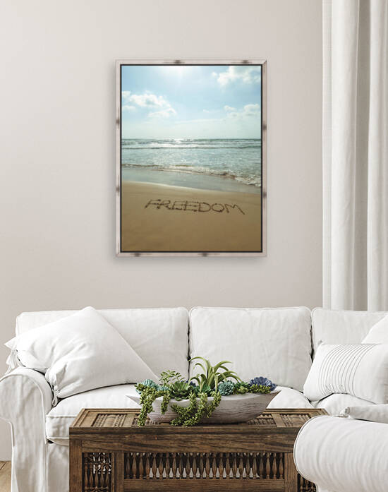 Word Freedom written in sand on the beach by Assaf Frank