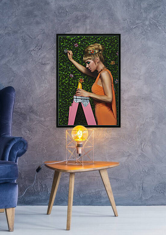 Beautiful young blonde woman with bangs wearing a light orange dress standing on a pink stepladder while picking some flowers on a wall of green leaves by Artmood Visualz