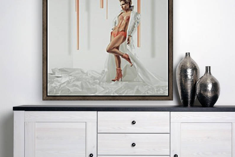 Fashion blonde model posing in a white long coat made of foam sheets standing in a wide white space with long pink sticks coming down the ceiling by Artmood Visualz