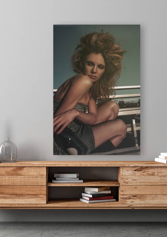 Vintage portrait of a tipsy beautiful young woman wearing an old school denim dress and long teased hair celebrating alone with champagne in the bleachers of a soccer field by Artmood Visualz