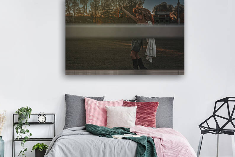 Vintage portrait of a tipsy beautiful young woman wearing an old school denim dress and long teased hair celebrating alone with champagne on a soccer field by Artmood Visualz