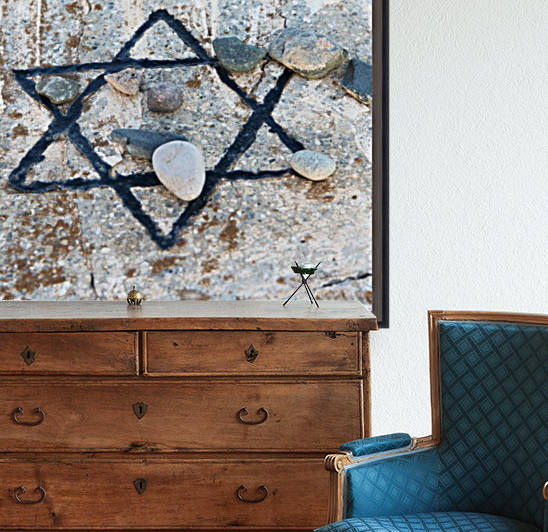 A star of david etched and painted on a rock with stones laying on it by PacificStock