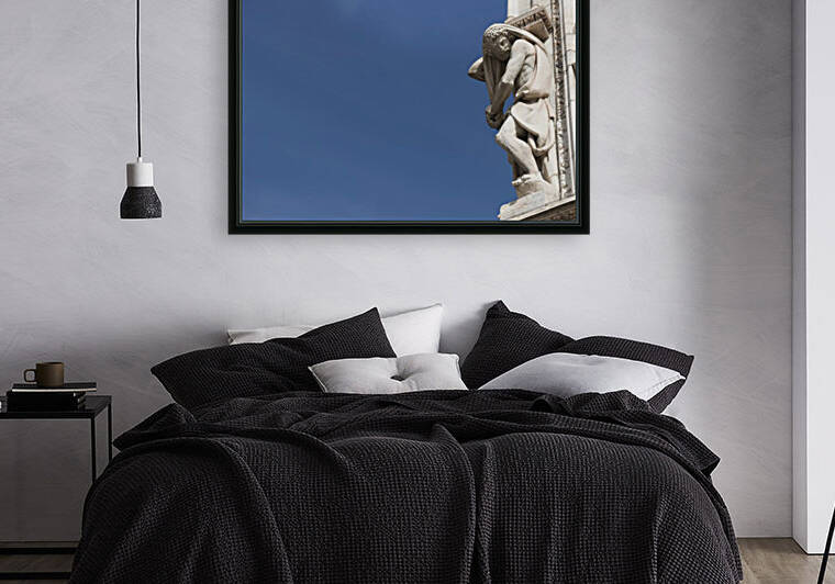 Carved sculpture of male likeness on the facade of Milan Cathedral against a blue sky; Milan, Lombardy, Italy by PacificStock